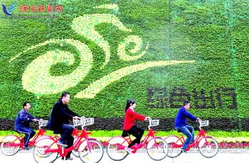 市民騎公共自行車路過市人民廣場一處花壇。記者 張馳